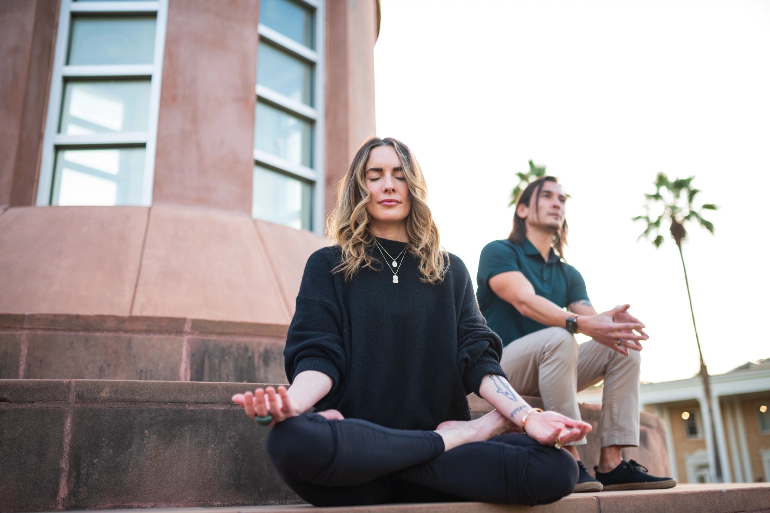 Woman meditating with man sitting behind her